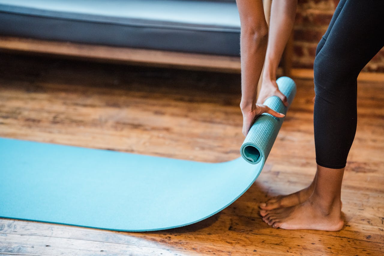 award-img Crop unrecognizable ethnic woman in leggings preparing yoga mat for training in studio in daytime